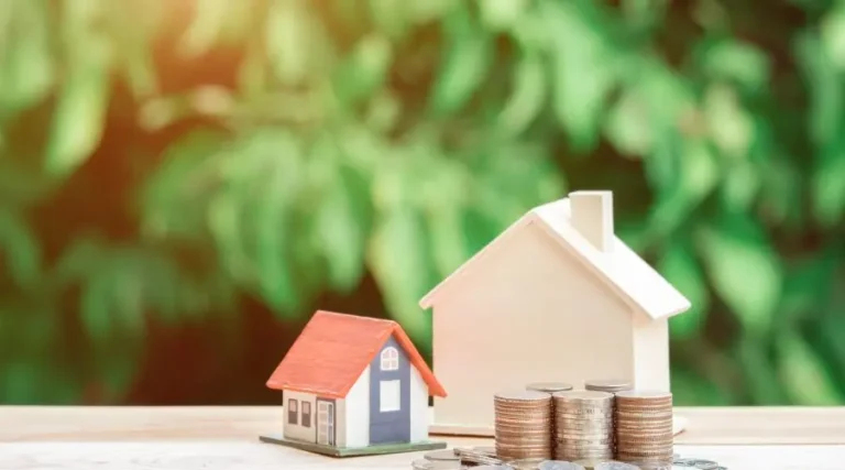 Petite et grande maisons posées sur une table avec des piles de monnaie