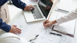 Mains de deux personnes et crayons sur un plan de maison